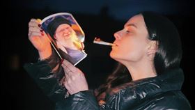 伊朗女性燃燒最高領袖照片來點煙，挑戰權威規範。（圖／翻攝自X平台 @visegrad24）