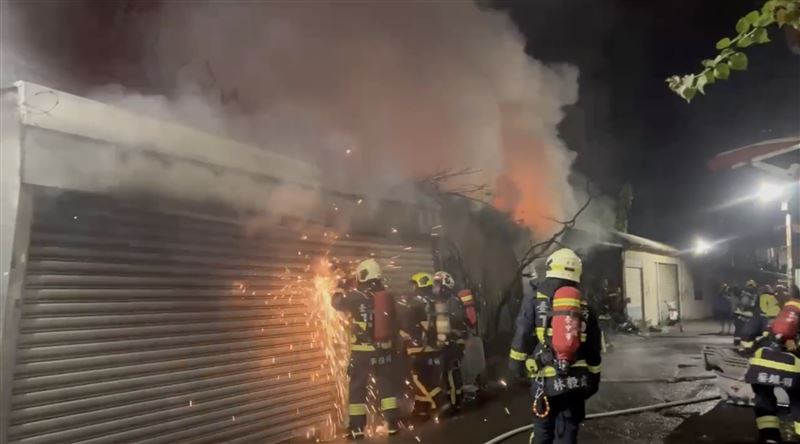 消防人員破壞鐵捲門進入工廠灌救。（圖／翻攝畫面）