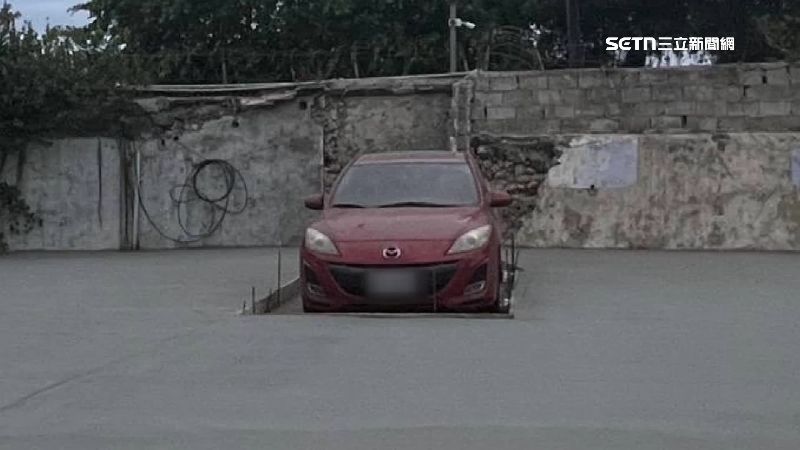 紅色轎車停空地上，周圍鋪滿水泥