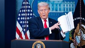 川普翻閱著厚厚一疊「政績」。（圖／美聯社／達志影像）