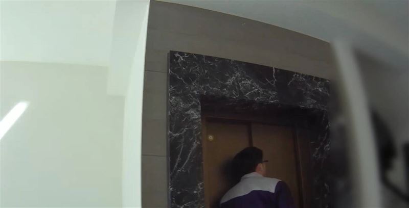 電梯工程人員敲擊1樓電梯門，呼喚受困的許姓女子，判斷人卡在頂樓。(圖／翻攝畫面)