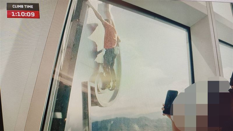 美國攀岩大神霍諾德(Alex Honnold)挑戰攀爬台北101。 粉絲隔玻璃窗打招呼(圖/翻攝畫面)
