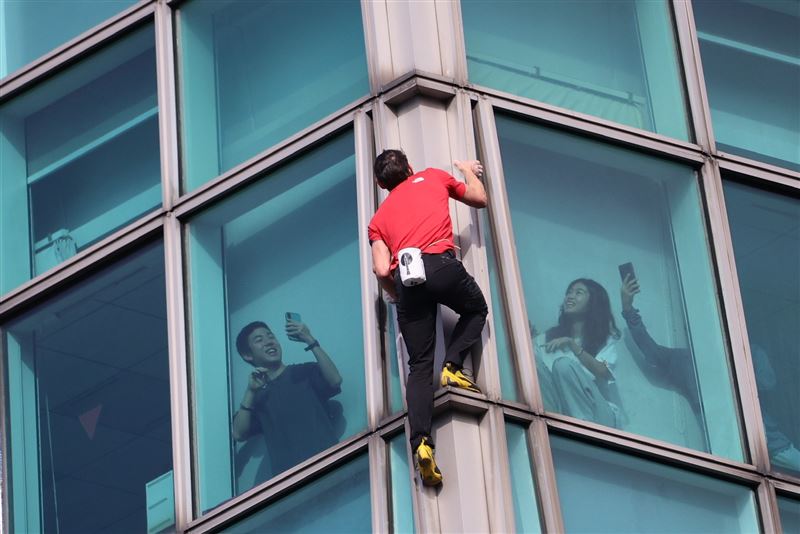 隨著高度不斷攀升，霍諾德神情輕鬆，抓點穩定，還不時對著窗內上班的101員工揮手致意。（圖／記者鄭孟晃攝影）