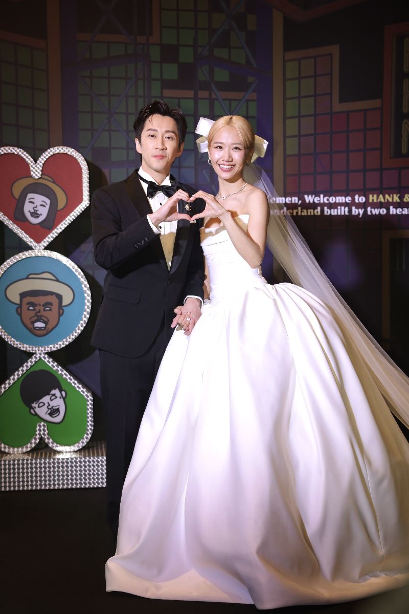 藝人黃路梓茵(Lulu)(右)、陳漢典(左)25日在台北文華東方酒店舉辦婚宴,兩人著禮服亮相,一起手比愛心甜蜜拍照。(圖/中央社)