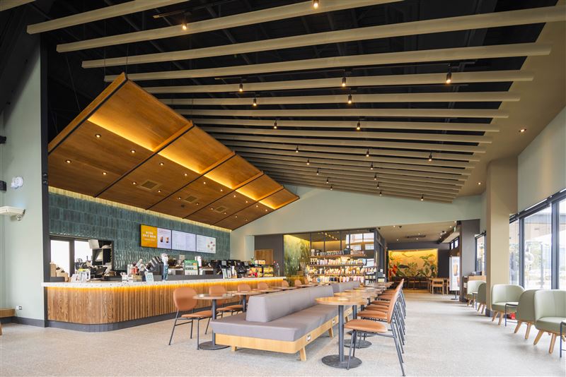 星巴克竹南大埔門市室內設計取材自農舍意象，以斜屋頂天花作為空間亮點，結合層次細膩的燈光設計，突顯吧台區域的視覺焦點。（圖／品牌業者提供）