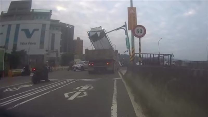 砂石車行經擺接堡路時，因車網架未收，導致紅綠燈號誌桿被勾住扯斷。（圖／翻攝畫面）