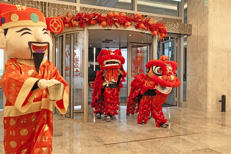 台北漢來喜迎馬躍新春豐年，大年初一大廳舞獅團迎春納吉，財神爺送福糖向旅人拜年賀歲。（圖／飯店旅宿業者提供）