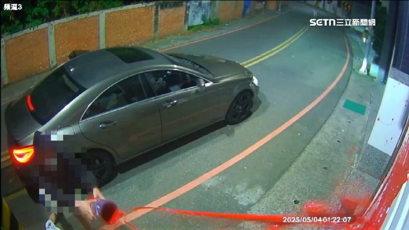 一名帽T男手拿紅油漆往大門潑