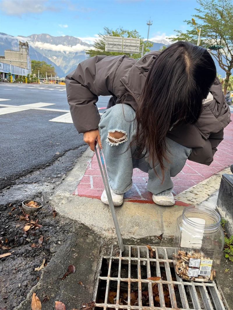 高中生拿著夾子，蹲下清理街道菸蒂。（圖／「高中生的循環經濟團體」顧問林立提供）