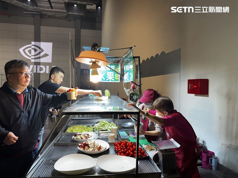 現場一角，通化街水果阿婆把平日使用的攤車直接推進輝達尾牙會場，燈具、檯面、器具都維持原樣，現切水果一杯一杯遞給排隊的員工。（圖／三立iNEWS提供）
