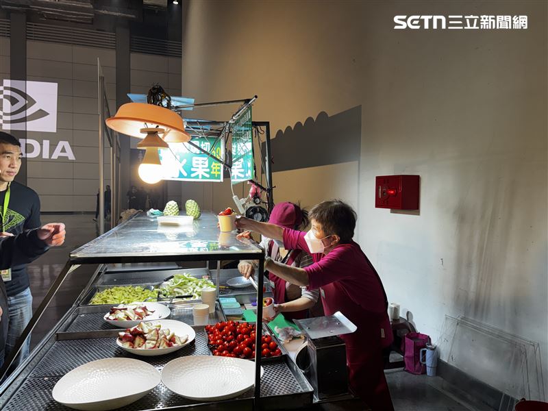 現場一角，通化街水果阿婆把平日使用的攤車直接推進輝達尾牙會場，燈具、檯面、器具都維持原樣，現切水果一杯一杯遞給排隊的員工。（圖／三立iNEWS提供）