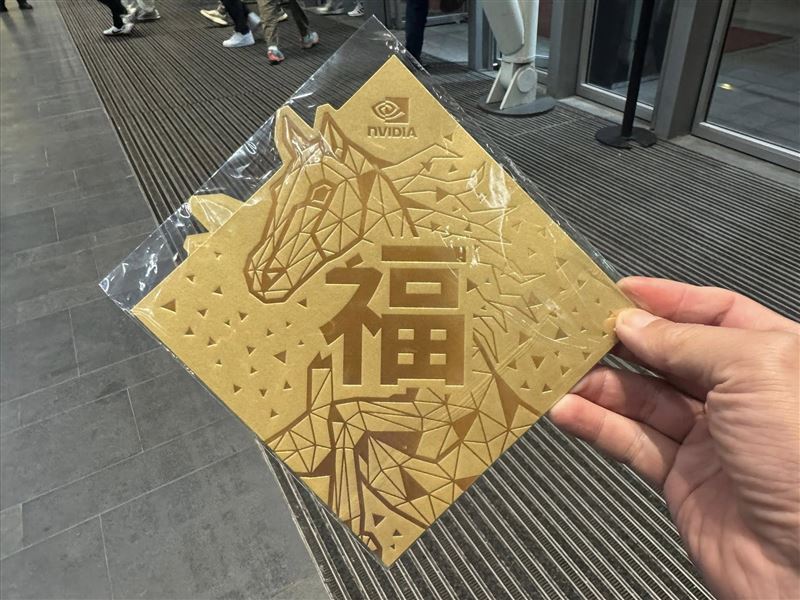 輝達旺年會展現細膩心思，入場即送「人人有獎」的特製伴手禮。採用象徵財富的金色系，並以幾何線條勾勒出「金馬」圖騰，除呼應2026馬年，更巧妙融入3D運算美學，讓這份充滿「AI信仰」的紅包袋成為現場最搶手的收藏品。（圖／記者師瑞德攝影）