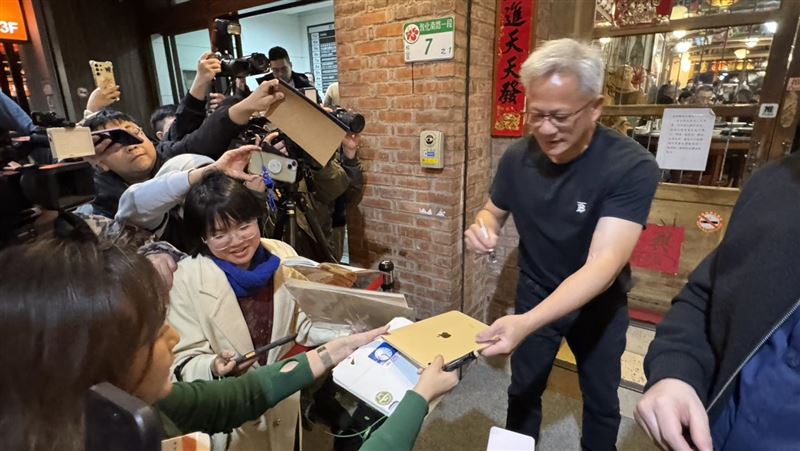 輝達執行長黃仁勳今晚在「磚窯」餐廳宴客,吸引大批粉絲包圍。現場一位街頭速寫畫家吳沁頤,自備板凳在喧鬧中即席作畫,以驚人速度捕捉黃仁勳神韻。她聽從《三立新聞網》記者的「戰略建議」調整卡位動線,果然成功等到黃仁勳現身互動,順利在剛完成的畫作上獲得親筆簽名,圓滿達成心願。(圖/記者余國棟攝影)