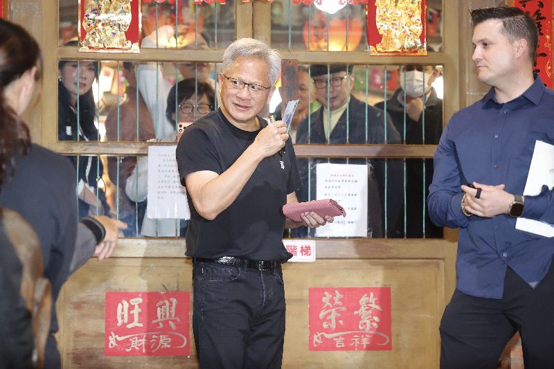 輝達（NVIDIA）執行長黃仁勳（中）31日晚間在台北宴請台灣供應鏈夥伴，在店外與粉絲互動時逗趣表示，幫粉絲簽錢包，那就得拿錢送給小孩子，或是交給店家當小費，隨後真的從錢包內拿出鈔票交給在場小朋友