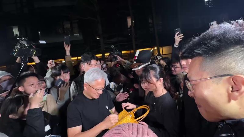 黃仁勳被民眾包圍人氣超旺，親切地幫女粉絲包包簽名。(圖/三立電視)