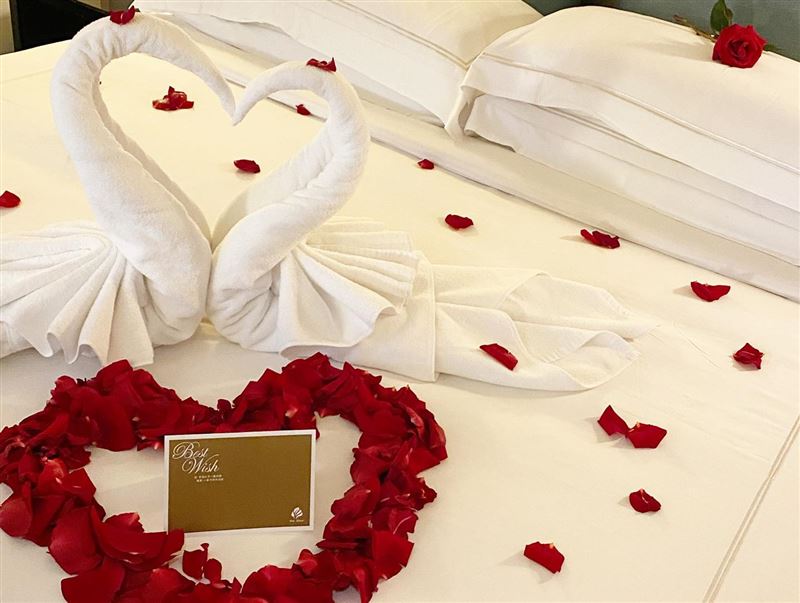 房間中特別以玫瑰花瓣及天鵝造型毛巾妝點，營造私密溫馨的浪漫時光。（圖／飯店旅宿業者提供）