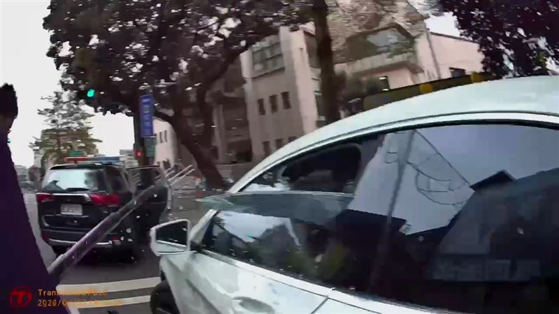 白色賓士車違規遭員警盤查，駕駛拒檢倒車後再往前加速逃逸，員警破窗制止。（圖／翻攝畫面）