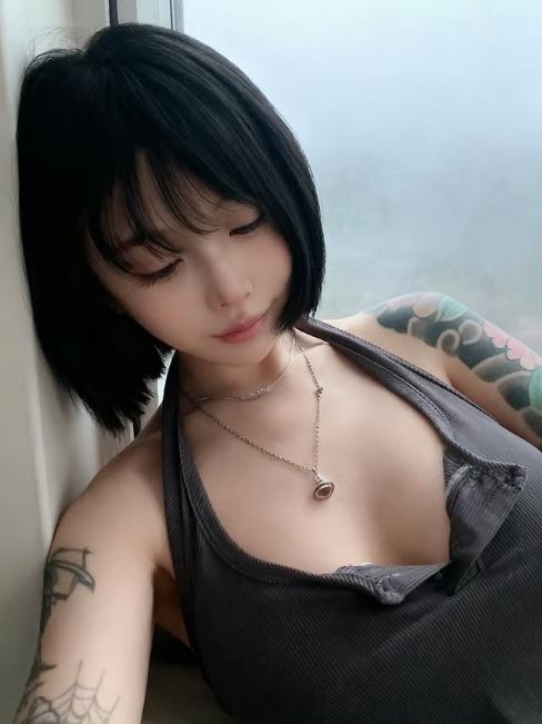 新加坡DJ網紅蘇櫻花有包手又包腳的大片的刺青，近期靠AI去除刺青，圓夢在日本出道拍AV。（圖／翻攝自Ｘ）