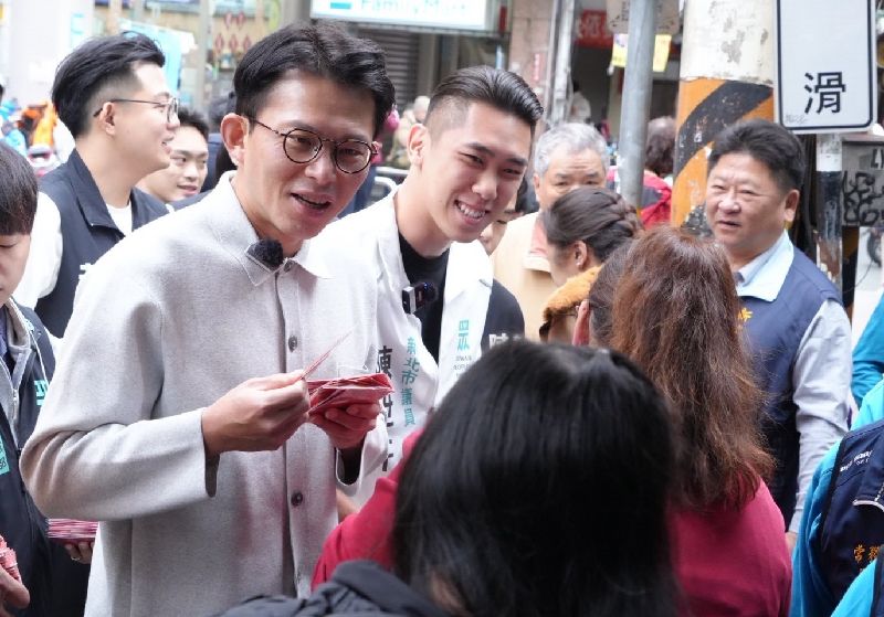 民眾黨新北市長參選人黃國昌（前左）17日與同黨議員陳世軒（後中）赴新莊武聖廟參拜、發放福袋，受訪時透露兩人已有通話，對於新北未來的願景、想法，彼此都敞開心胸交換意見。（民眾黨提供）