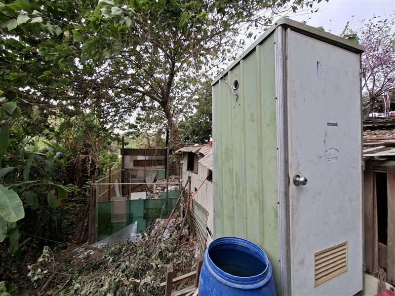 堆放裝潢廢棄物的平台旁還有堆滿碎磁磚的工寮及簡易廁所。(圖／翻攝畫面)