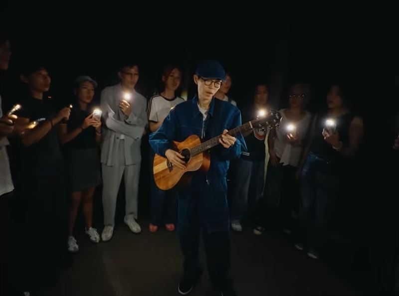 〈才二十三〉MV中,方大同出現壓軸畫面,在人群裡背著吉他自彈自唱。(圖/翻攝自Khalil Fong 方大同 YT)