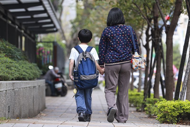 台北市率先推出「育兒減少工時」試辦計畫，3月1日開放申請，提供12歲以下子女確有接送需求的家長申請減少1小時工時。圖為1日有家長牽著孩子步行