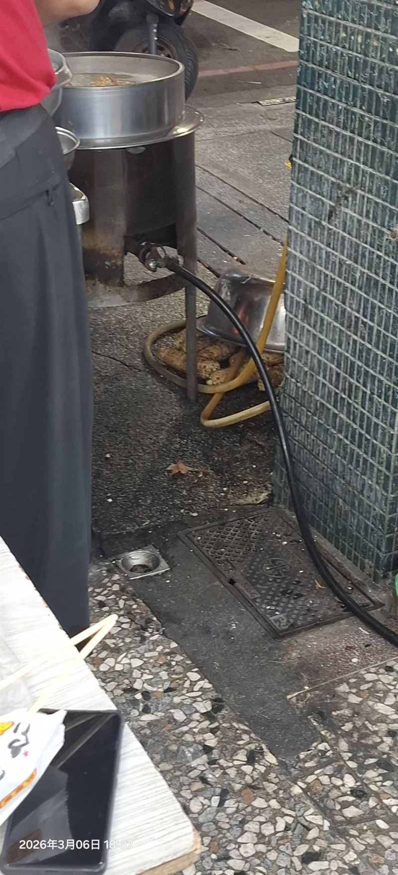 民眾指控老闆娘將洗過的烤玉米堆在水溝蓋上，隨後直接放進鍋內烹煮。（圖／翻攝自爆料公社）