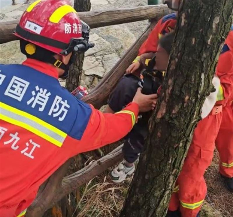消防隊員繫上安全繩滑落深谷，成功將縮在樹叢中哭喊的男童救回。(圖/微博)