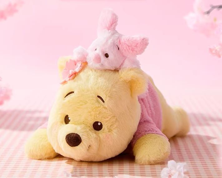 MINISO南紡正櫃首波主打系列之一「櫻花祭維尼趴姿公仔」，維尼與小豬舒適柔順的絨毛外觀可愛滿點，引爆粉絲收藏熱潮。（圖／品牌業者提供）