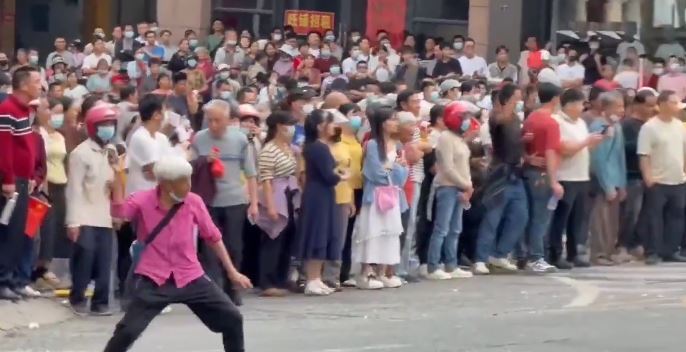 一位滿頭白髮的女村民無懼威嚇，憤而拿起雞蛋投向警方。（圖／翻攝自微博）