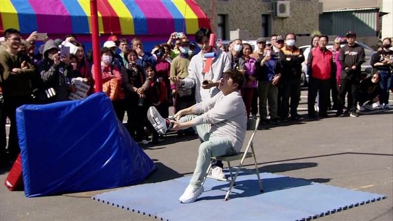 「三府千歲祈福賽」遊戲的第一關需要腳綁紅線，努力抬腳讓紅包下降，咬到紅包才算成功。（圖／民視提供）