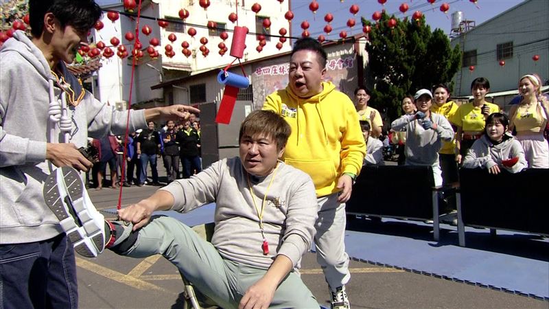 瓜哥（前排中）挑戰「抬腳咬紅包」屢試不成，董至成（前排右）決定出手救援。（圖／民視提供）