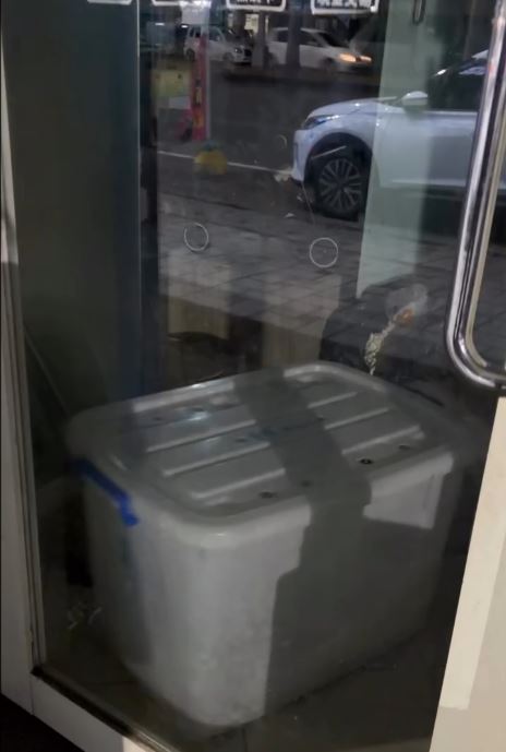 民眾路過寵物店發現收納箱內傳出淒厲狗叫聲，且箱子不斷碰撞玻璃門。（圖／民眾提供）