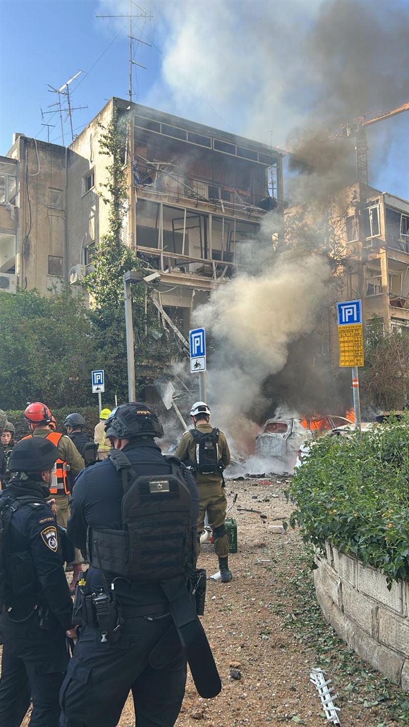 以色列大城特拉維夫於24日早晨，遭到伊朗空襲，大樓外牆全毀，前方的白色汽車失火冒出濃煙。（圖／翻攝自X平台 @Mdais）