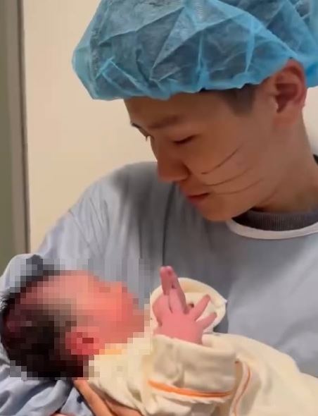 林嘉珍同步公開多張溫馨畫面，只見林嘉珍身穿淺藍色防護衣，小心翼翼抱著新生兒，眼神滿是柔情。（圖／翻攝自林嘉珍IG）