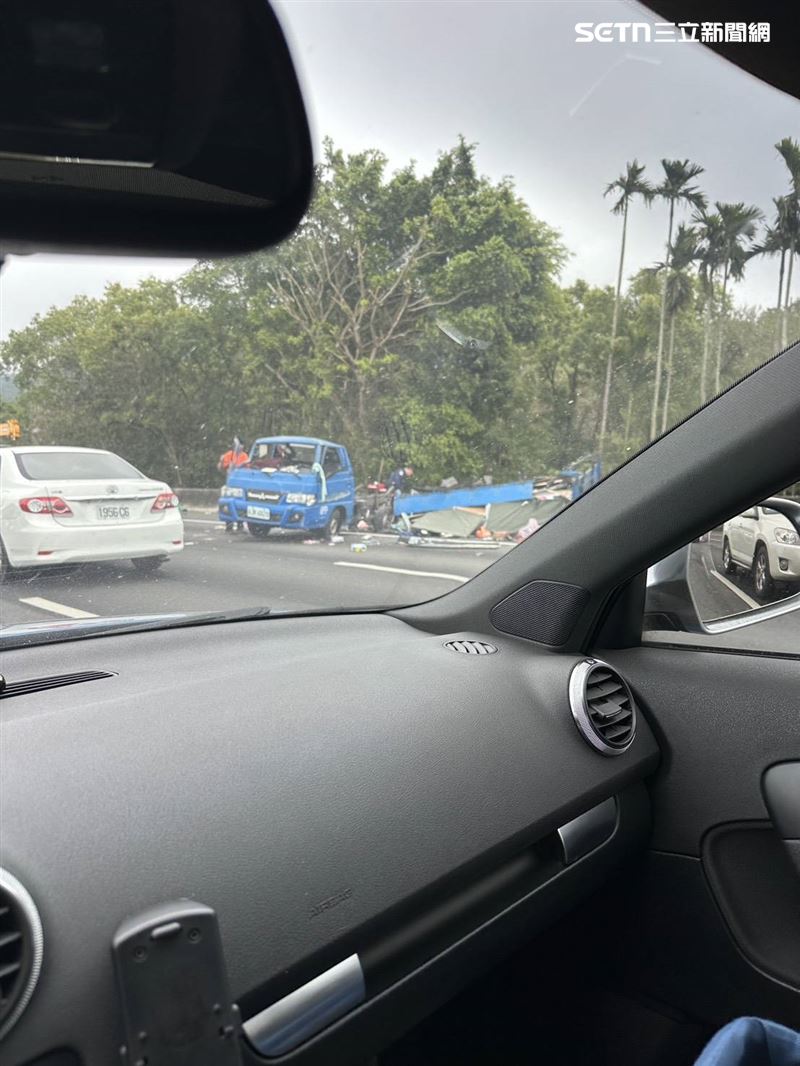 一名男性傷者坐在護欄邊,表情痛苦地等待救援,身上有多處血跡。(圖/翻攝畫面)