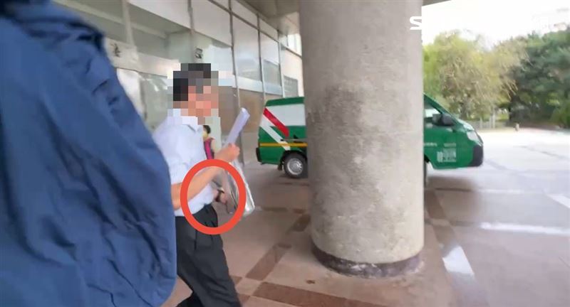邱姓副院長左手套上監控手環，見到媒體急忙以外套罩頭，狼狽抱頭狂奔。（圖／翻攝畫面）
