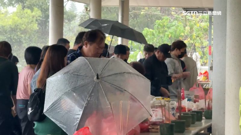 民眾撐傘是為了幫供品遮雨