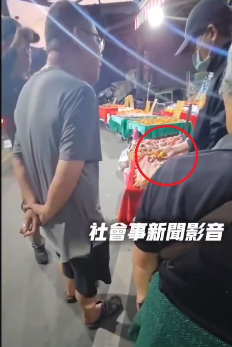 男性竊嫌在店家的枇杷攤位前佯裝挑選，隨後趁人不注意，徒手拿走兩顆枇杷並迅速放進外套口袋內 。(圖/翻攝畫面)