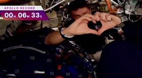 指揮官里德懷斯曼在艙內比出愛心手勢，向女兒們傳達思念。（翻攝NASA YouTube頻道）
