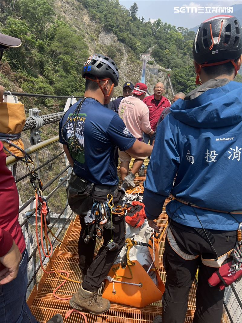 警消在溪床的兩塊巨石間尋獲死者，透過吊掛方式運出遺體。（圖／翻攝畫面）