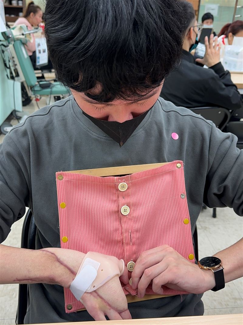 小均(化名)復健練習扣衣服扣子等生活自理能力。(圖／陽光基金會提供）