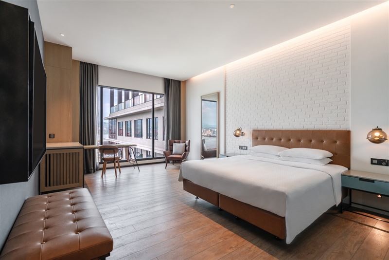 台北八里福朋喜來登酒店即日起至6月30日，「十年磨一劍 淡江大橋紀念」住房專案，最低每房每晚9,570元起，旅人除了可享雙人早餐、下午茶，更可獲得通車紀念磁鐵等好禮，圖為豪華河景客房。（圖／飯店旅宿業者提供）