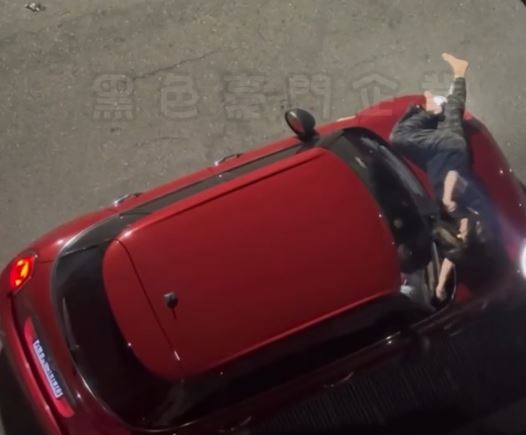 男子一度欲駕車離開，女子見狀竟直接躺在引擎蓋上拍打擋風玻璃阻止其離去。（圖／翻攝畫面）
