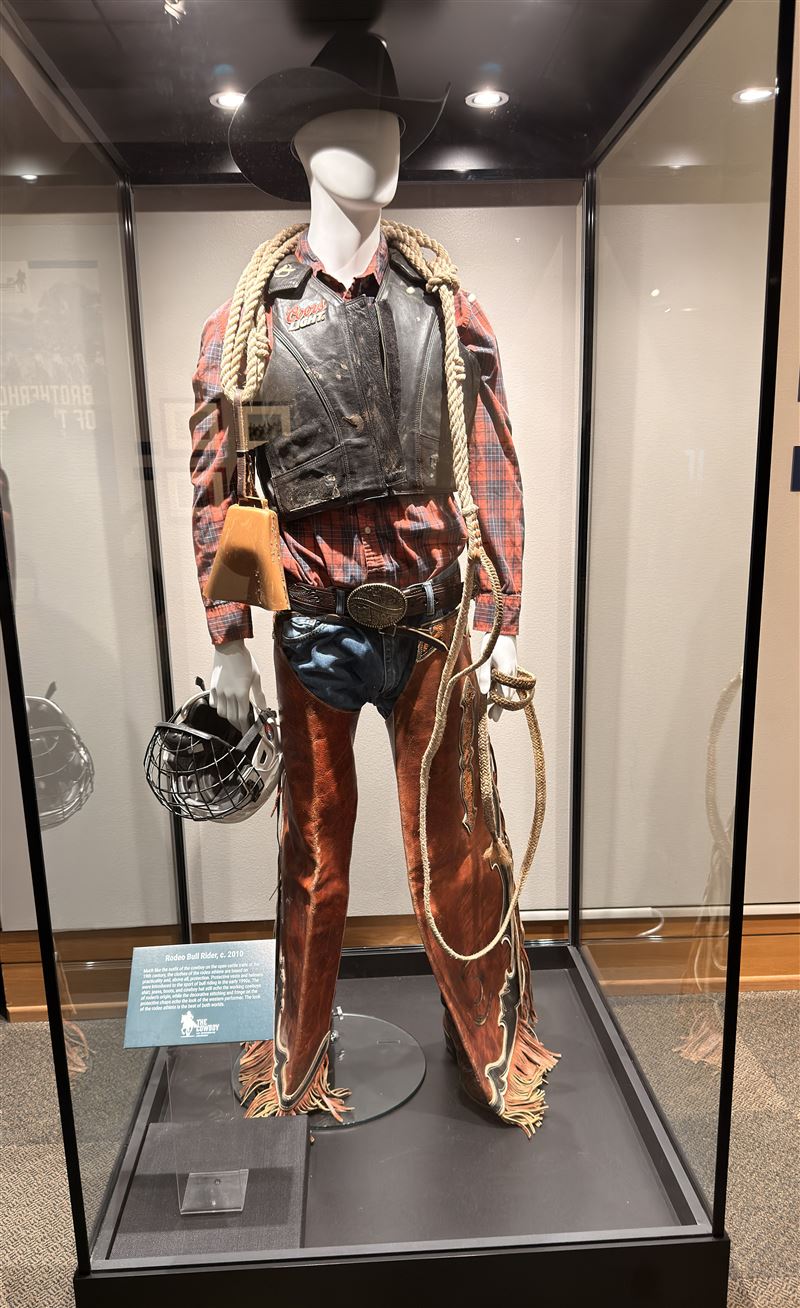 展區公開2010年代牛仔騎士（Rodeo Bull Rider）標準裝備，包含防護背心、安全頭盔與流蘇皮褲，呈現現代競技牛仔融合實用防護與西部風格的文化特色。（圖／記者蕭翰弦攝影）