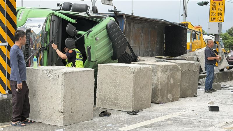 砂石車不明原因失控暴衝,自撞路側護欄後翻覆,車上的大石塊也散落滿地。(圖/翻攝畫面)