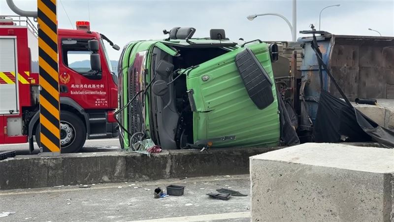 砂石車不明原因失控暴衝,自撞路側護欄後翻覆,車上的大石塊也散落滿地。(圖/翻攝畫面)