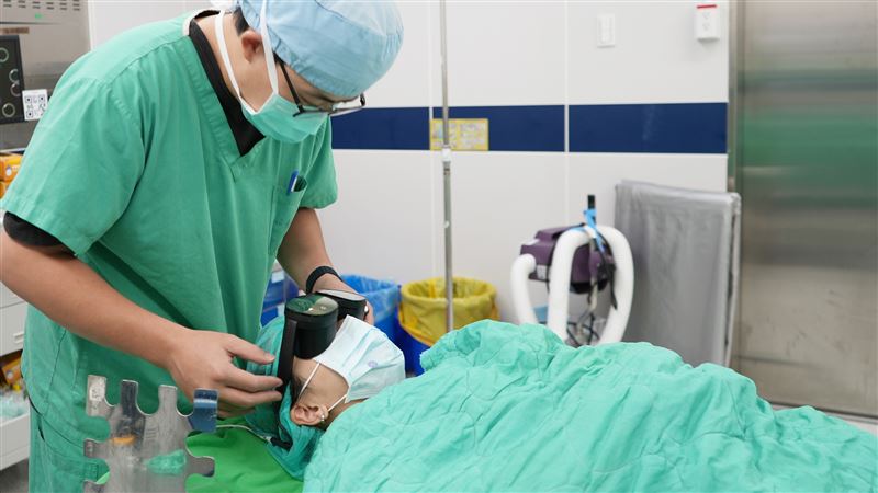 江禮仰副護理長為病人調整及配戴VR眼鏡。(圖/臺北醫院提供)