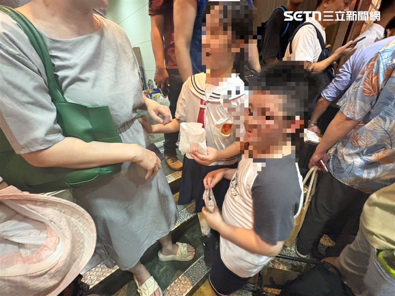 黃仁勳二度走出餐廳，手上拿熱騰騰的「香菇流沙包」他注意到一對姐弟，立刻親切地招手示意兩人上前領取「香菇流沙包」。面對突如其來的幸運時刻，姐弟倆顯得有些不知所措，似乎還不知道自己已成為全場羨慕的焦點，只是單純因為拿到美食而露出開心笑容，也讓人看見最純粹、最簡單的童年快樂。（圖／記者王文承攝影）