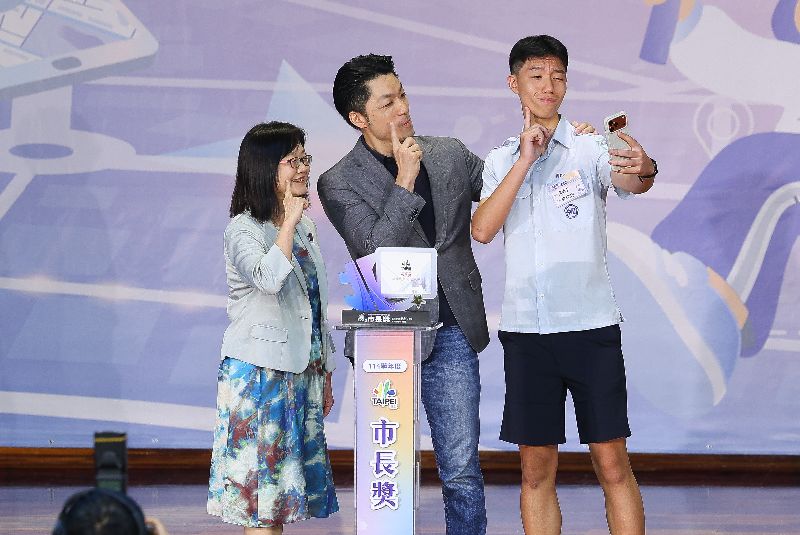 台北市長蔣萬安6月7日下午在大安高工出席台北市公私立國中114學年度畢業生市長獎頒獎典禮,他的兒子蔣得立(右)是市長獎得主,兩人在台上俏皮互動合影。(圖/中央社)